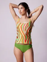 Tankini de dos piezas, musculosa con estampado de círculos negros y verdes sobre fondo blanco, con escote cuadrado, copa armada y sujetador interno. Incluye bombacha negra lisa.