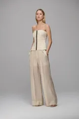 Pantalón de corte amplio y tiro alto, confeccionado en tejido ligero con paneles laterales transparentes y pliegues frontales. Presenta un diseño de pernera ancha con caída fluida y bolsillos laterales.