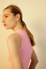 Top crop de tejido de punto color beige claro, con cuello redondo y manga sisa. Presenta acabados en rib en el cuello, sisas y bajo.