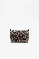 Bolso tipo neceser de terciopelo con estampado animal print de cebra, cierre superior y detalle de borla decorativa con cuentas en el lateral.