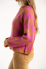 Sweater de punto con diseño de rombos en colores fucsia y tostado, cuello redondo y mangas largas.