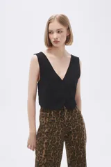 Top tipo chaleco negro, con escote en V, cierre frontal con botones y corte al cuerpo.