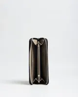 Billetera negra de símil cuero con cierre perimetral, detalles de tachas plateadas en el contorno y parche frontal con el logo de la marca Extra Large.