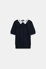 Jersey de punto negro de manga corta con cuello solapa blanco en contraste, decorado con abalorios joya y lentejuelas. Presenta cierre trasero con abertura y botón.