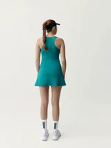 Vestido deportivo turquesa con sujetador integrado y copas extraíbles, confeccionado en tejido Shapplex_B, compacto y ligero. Cuenta con puntos reflectantes en la espalda y diseño de corte evasé con short interno.