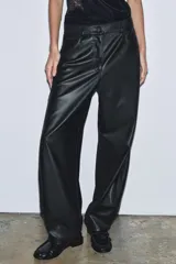 Pantalón de tiro medio confeccionado en tejido efecto piel. Presenta un diseño de pierna ancha tipo balloon, cintura con trabillas, cierre frontal con cremallera y botón, y cinco bolsillos.