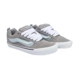 Championes Vans modelo Knu Skool, de diseño robusto y acolchado. Presentan una capellada de gamuza en color gris con la icónica banda lateral Sidestripe en tono celeste claro. Cuentan con cordones gruesos blancos, lengüeta y cuello acolchados, y suela de goma blanca con la clásica banda negra.