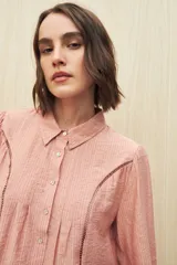 Camisa blanca de manga larga con cuello clásico y botones de nácar. Presenta detalles calados en el frente.