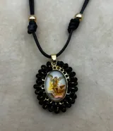 Collar ajustable con cordón azul y dije central ovalado con imagen religiosa, rodeado por una estructura de cuentas multicolores.