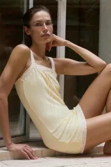 Vestido mini de corte recto en color amarillo suave, con tirantes anchos, escote recto con detalles de encaje a tono y un delicado lazo frontal.
