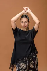 Remera negra de corte holgado con cuello redondo y mangas cortas. Presenta un diseño asimétrico en el ruedo con detalle de encaje negro.