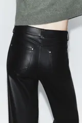 Pantalón de tiro medio confeccionado en tejido efecto piel, con diseño de cinco bolsillos y cierre frontal con cremallera y botón.