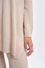 Buzo de punto oversize color beige, con cuello redondo, mangas largas y corte holgado.