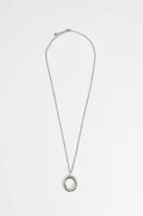 Collar de cadena fina plateada con un dije circular de diseño orgánico e irregular en acero quirúrgico.