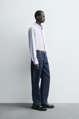 Camisa de corte regular fit confeccionada en popelín de algodón. Presenta cuello abotonado, manga larga con puños ajustables mediante botón y cierre frontal de botonadura completa.