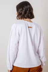 Remera de algodón color azul marino, con cuello redondo fruncido y mangas largas abullonadas con puños elásticos.