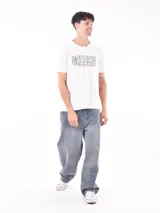 Remera de manga corta color gris topo, corte slim, con cuello redondo y un estampado gráfico en el pecho que combina texto manuscrito con un diseño abstracto en tonos oscuros.