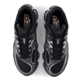 Championes urbanos New Balance modelo 2000, color negro con detalles en gris plateado. Presentan una estructura de malla transpirable con refuerzos sintéticos, cierre de cordones y una suela con tecnología de amortiguación visible.