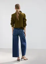 Jeans de denim azul de corte wide leg, tiro medio y diseño clásico con bolsillos y cierre frontal.