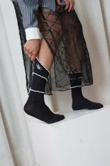 Medias negras de diseño acanalado, con detalles de costuras blancas onduladas y logo bordado en la parte superior.