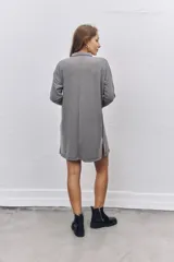 Vestido corto de tejido acanalado en color gris, con cuello polo, cierre frontal de botones y mangas largas con caída de hombros.