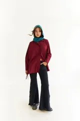 Camisa oversize de corte holgado con estampado de rayas verticales. Presenta cuello camisero, cierre frontal con botones a contraste y cordones integrados en la cintura para ajustar la silueta. Posee mangas largas con puños rectos.