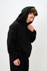 Canguro negro con capucha, cordones ajustables y bolsillo tipo canguro.