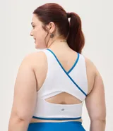 Top deportivo femenino confeccionado en microfibra, de color blanco con vivos en azul, escote redondo, copa y breteles anchos.