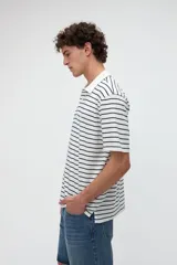 Remera polo de manga corta con diseño a rayas horizontales marrones sobre base blanca, cuello camisero en color blanco con media cartera de botones y aberturas laterales en el dobladillo.