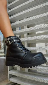 Borcegos negros de cuero sintético con plataforma y cordones. Presentan una tira con apliques metálicos alrededor del tobillo y cierre lateral con cremallera.
