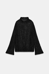 Camisa de hilatura con viscosa color negro, con cuello subido y manga larga ancha. Presenta aplicaciones de abalorios combinados a tono en toda la prenda y bajo recto.