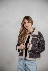 Campera de gamuza con estampado de leopardo en tonos grises, con interior y bordes de corderito sintético color crema. Presenta cierre frontal con botones tipo toggle y diseño de corte recto.