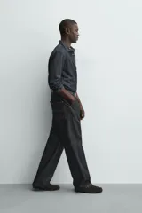 Pantalón chino de denim de algodón rígido, color índigo oscuro sin lavar. Corte baggy fit, tiro medio, con bolsillos frontales y traseros de plastrón. Presenta bordados a contraste en la cintura y en el bolsillo trasero.