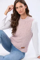 Chaleco tejido color rosado, con cuello redondo y diseño de ochos en el frente. Tiene un parche de cuero sintético marrón con el logo de la marca en el bajo.