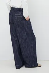 Pantalón de jean azul oscuro de tiro alto, con diseño holgado de pierna ancha, pinzas en la cintura y costuras a la vista.