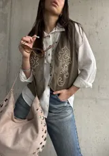 Chaleco verde militar de gamuza, con bordados en hilo crudo, diseño de flores y detalles de tachas metálicas.