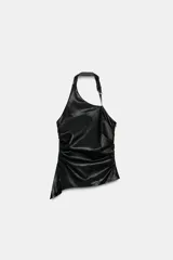 Top de cuello halter con hebilla metálica ajustable, diseño sin mangas y espalda descubierta. Presenta frunces laterales que crean un efecto drapeado y un bajo asimétrico. Cuenta con cierre lateral con cremallera oculta.