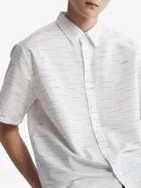Camisa blanca de manga corta con estampado de líneas horizontales azules y logos de Calvin Klein.