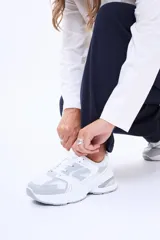 Championes casuales de diseño chunky en color blanco con detalles en gris, confeccionados en poliuretano y malla transpirable, con suela gruesa y cordones tono sobre tono.