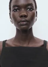 Top negro sin mangas, de corte recto y cuello cuadrado, con tirantes anchos y lazos decorativos en la espalda.