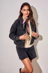 Campera oversize de denim negro, con cuello camisero, cierre frontal con botones y bolsillos ojal.