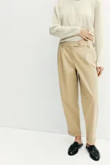 Pantalón chino de tiro medio, corte recto y holgado, con pinzas en la parte delantera. Presenta bolsillos laterales, falsos bolsillos traseros con solapa y bajo con dobladillo vuelto. Cierre frontal con cremallera y botones.