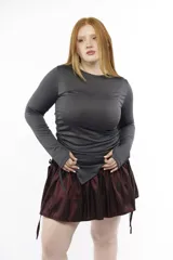 Top de manga larga color gris oscuro, confeccionado en jersey elástico. Presenta un diseño asimétrico con jaretas laterales regulables que permiten ajustar el largo y el volumen, además de aberturas para los pulgares en los puños.