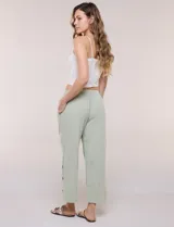 Pantalón de algodón rústico color verde, de tiro medio-alto con pretina elastizada y bolsillos laterales. Presenta corte holgado, diseño cropped de pierna ancha y aberturas laterales en los tobillos con detalles de botones.