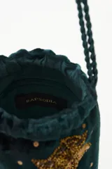 Cartera tipo bolso de mano color negro, confeccionada en terciopelo con bordados de estrellas y aplicaciones de pedrería brillante. Cuenta con correas trenzadas de cordón negro y cierre superior.