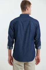 Camisa de jean azul oscuro de manga larga con cuello abotonado y bolsillo en el pecho.