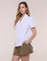 Blusa blanca de algodón texturizado con sutil relieve de rayas verticales al tono, escote en V con cuello solapa pequeño y mangas cortas.