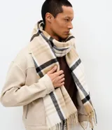 Bufanda de punto suave con estampado de cuadros en tonos beige, blanco y negro, con terminaciones de flecos en los extremos.