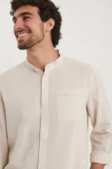 Camisa de cuello mao y manga larga, confeccionada en una mezcla de lino y algodón. Presenta un diseño de corte recto con botones en tono natural y un bolsillo pequeño en el pecho.