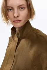 Campera corta verde militar en mezcla de lino, con cuello elevado, mangas raglán, bolsillos frontales con solapa y botones, y cordón ajustable en el bajo.